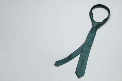 Photo of Green necktie on light background, top view. Space for text