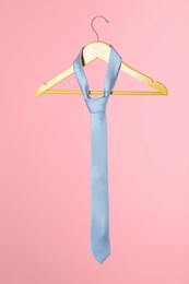 Hanger with light blue tie on pink background