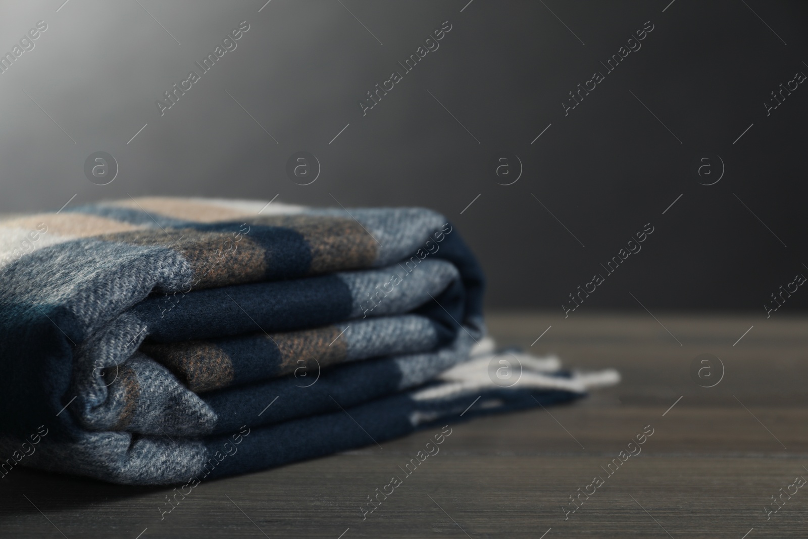 Photo of Soft checkered scarf on wooden table, space for text