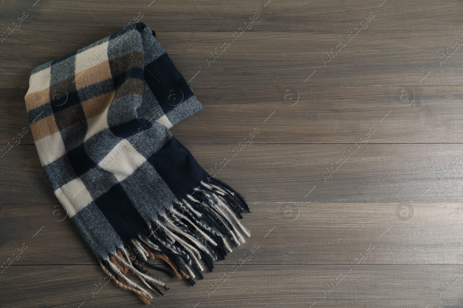 Photo of Soft checkered scarf on wooden table, top view. Space for text