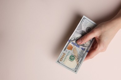 Photo of Money exchange. Woman holding dollar banknotes on beige background, top view. Space for text