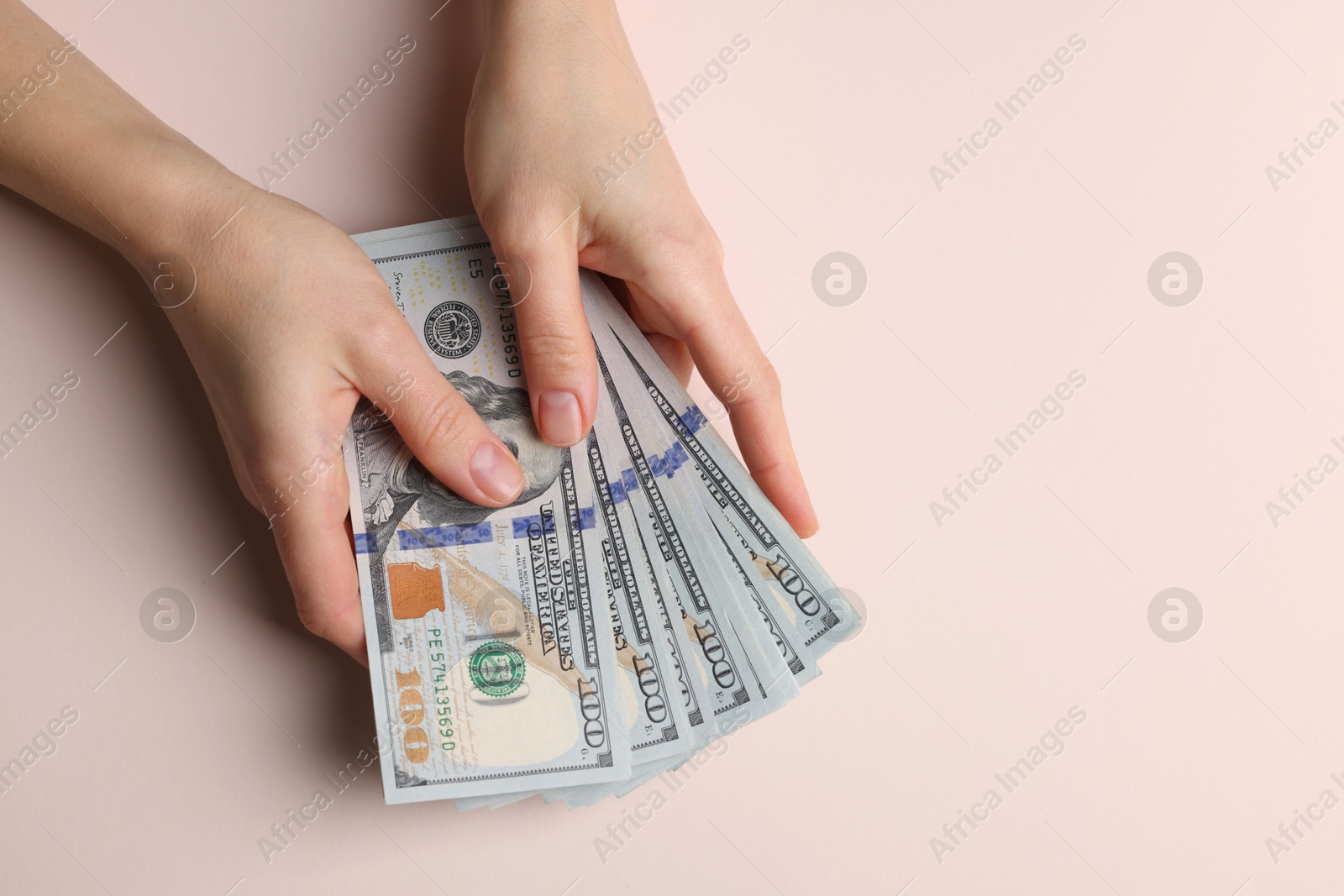 Photo of Money exchange. Woman holding dollar banknotes on beige background, top view. Space for text