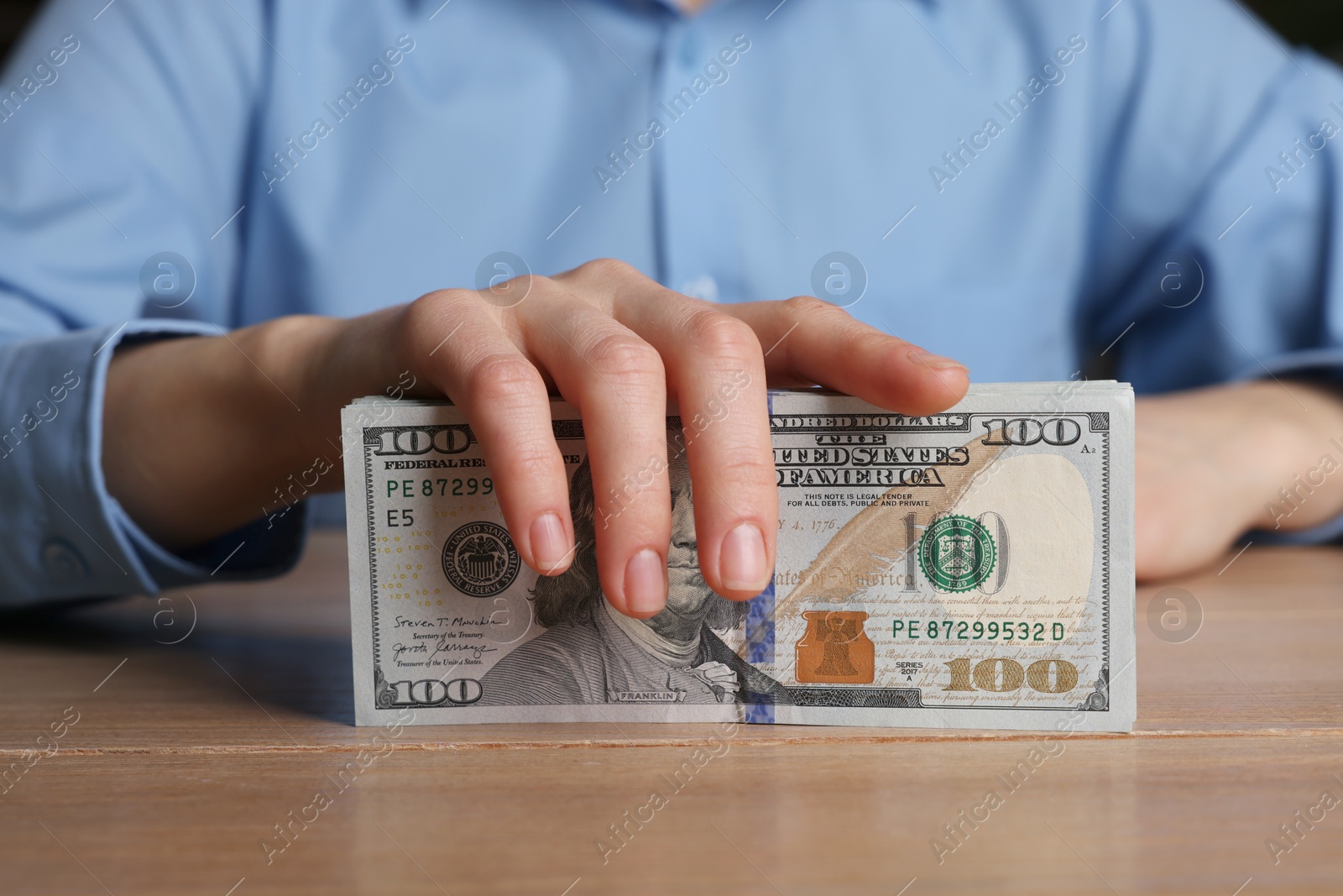 Photo of Money exchange. Woman holding dollar banknotes at wooden table, closeup