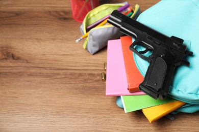 Photo of Gun, bullets and school stationery on wooden table, above view. Space for text