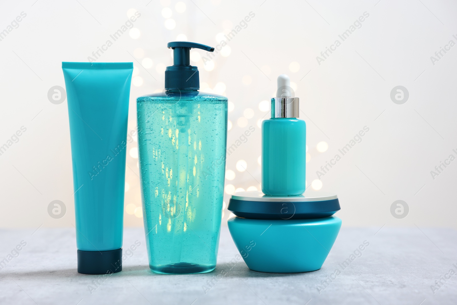 Photo of Set of hair care cosmetic products on gray table against light background