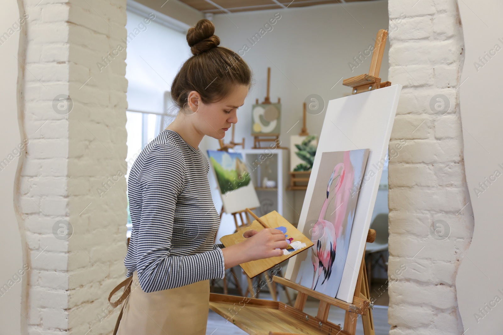 Photo of Woman drawing on easel with canvas in studio