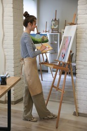 Woman drawing on easel with canvas in studio