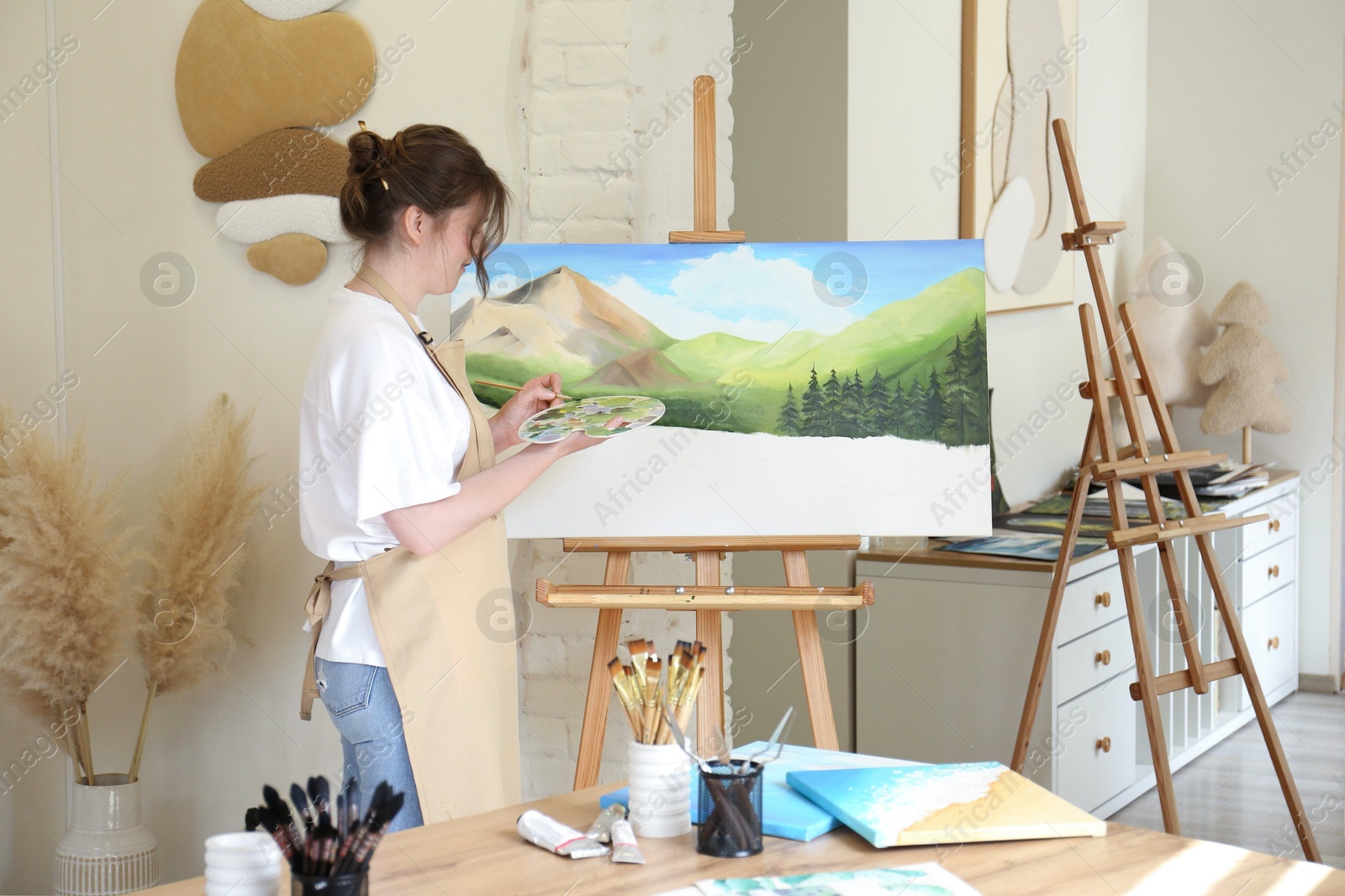 Photo of Woman drawing landscape with brush in studio