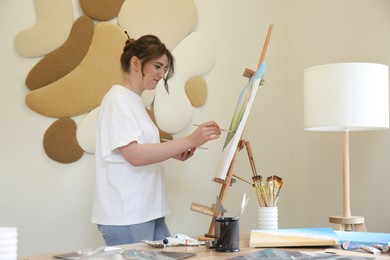 Photo of Woman drawing landscape with brush in studio