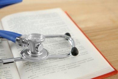 One new medical stethoscope on wooden table, closeup