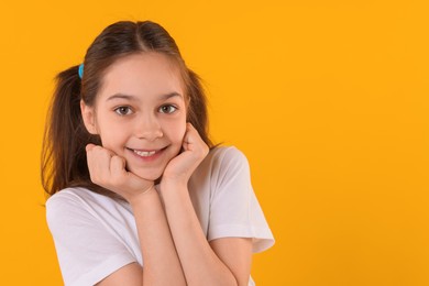 Photo of Portrait of happy girl on orange background, space for text