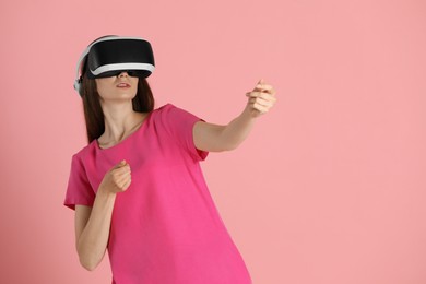 Photo of Woman using virtual reality headset on pink background, space for text