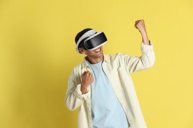 Smiling man using virtual reality headset on yellow background