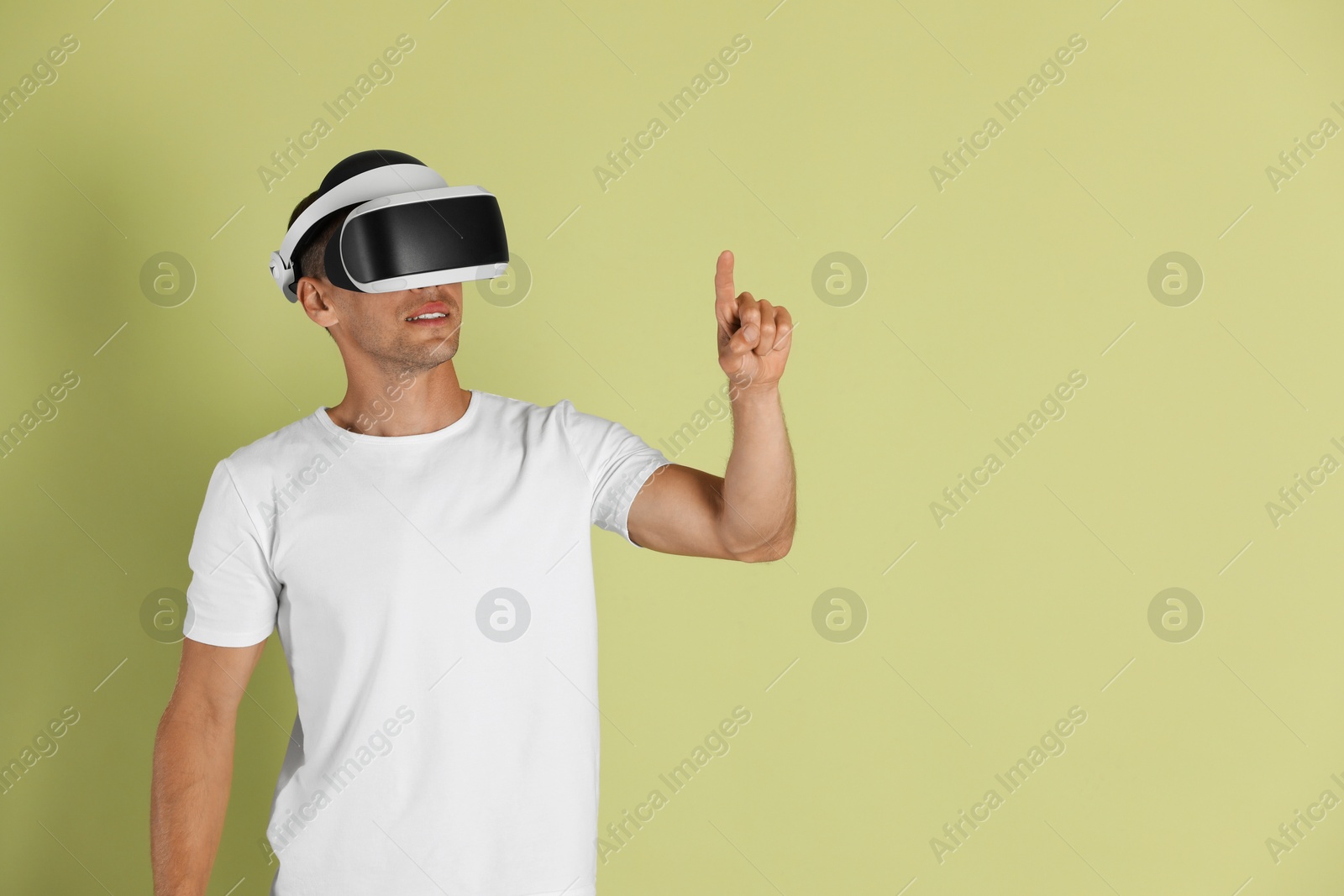 Photo of Smiling man using virtual reality headset on light green background, space for text