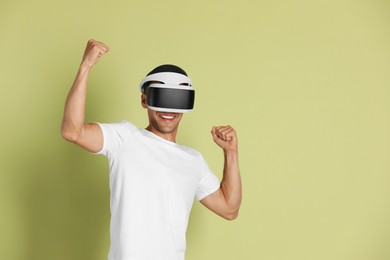 Smiling man using virtual reality headset on light green background