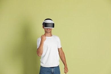 Photo of Smiling man using virtual reality headset on light green background