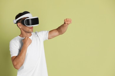 Photo of Man using virtual reality headset on light green background, space for text