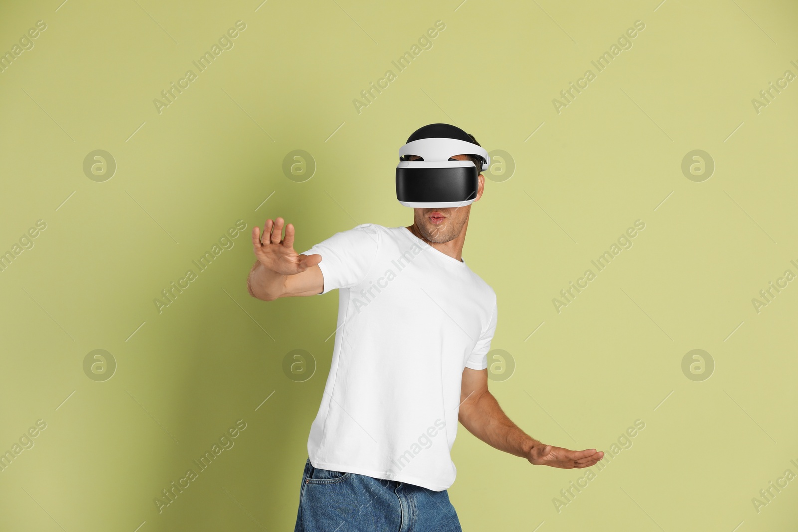 Photo of Man using virtual reality headset on light green background