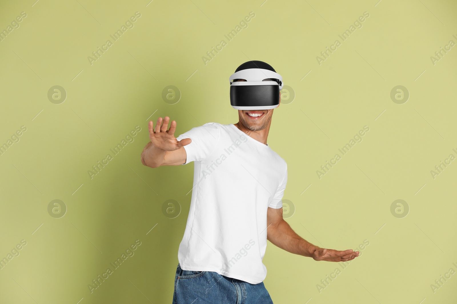 Photo of Smiling man using virtual reality headset on light green background