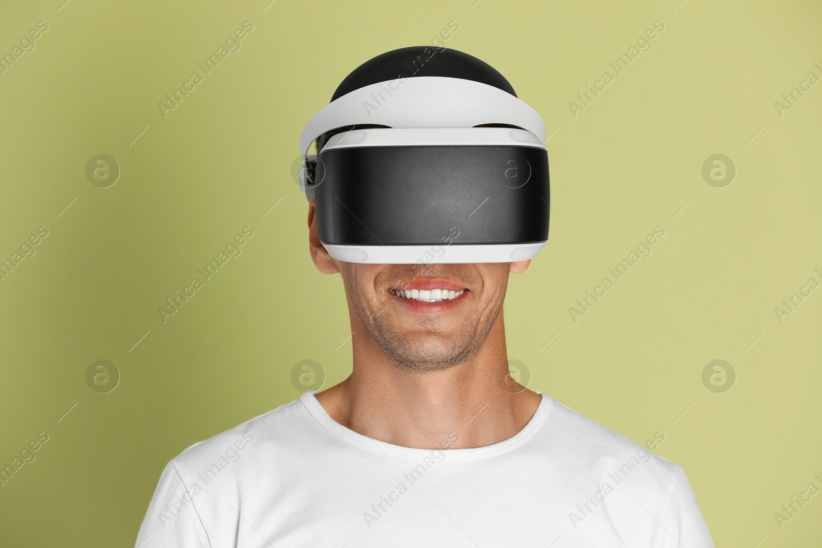 Photo of Smiling man using virtual reality headset on light green background