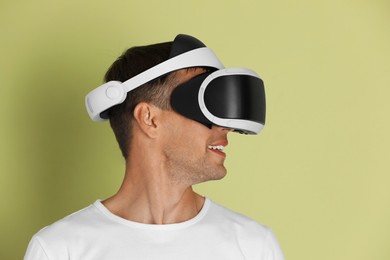 Photo of Smiling man using virtual reality headset on light green background