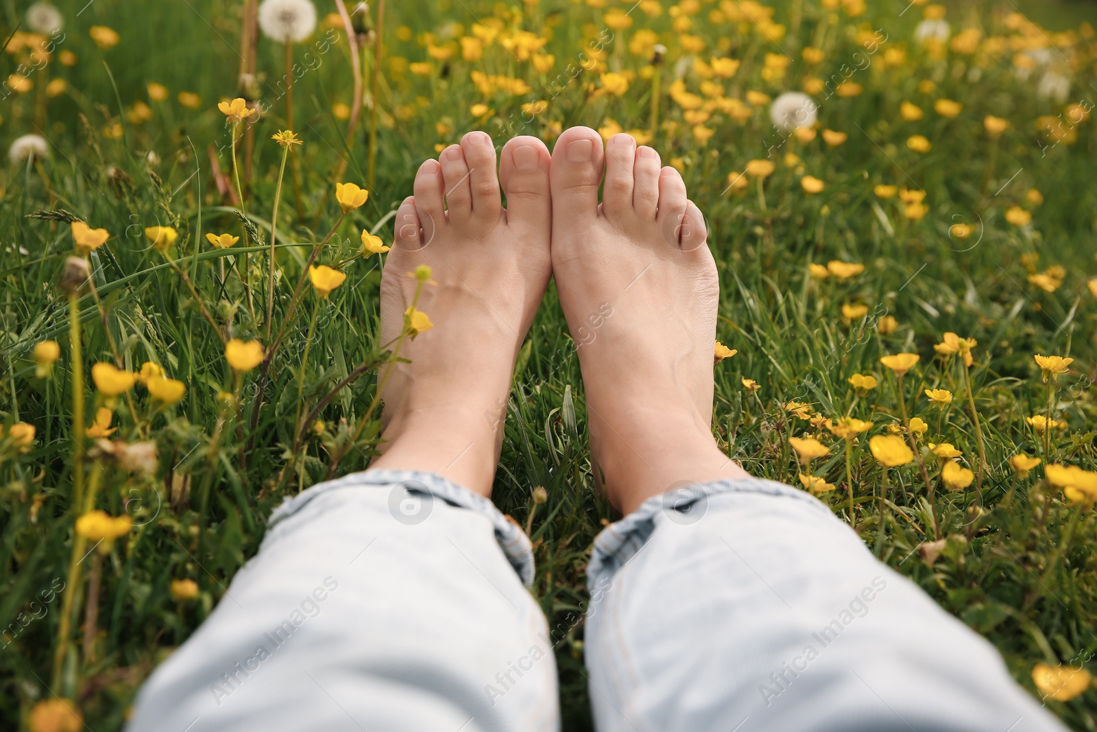 Photo of Woman sitting barefoot on green grass outdoors, closeup