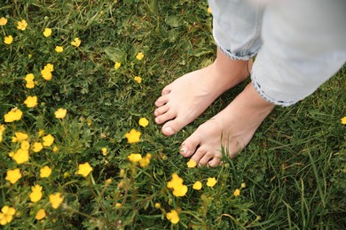 Woman walking barefoot on green grass outdoors, top view. Space for text