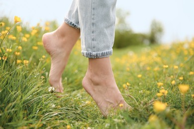 Woman walking barefoot on green grass outdoors, closeup