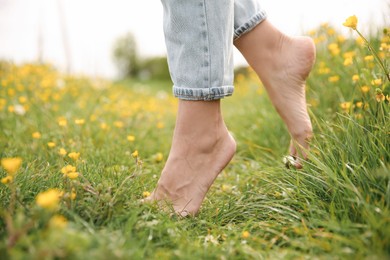 Photo of Woman walking barefoot on green grass outdoors, closeup