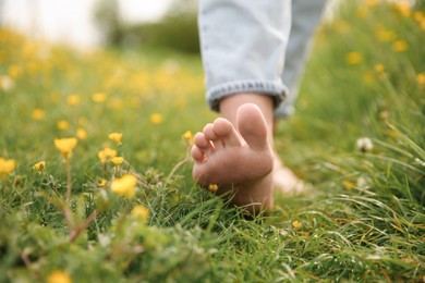 Photo of Woman walking barefoot on green grass outdoors, closeup