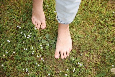 Photo of Woman walking barefoot on green grass outdoors, top view