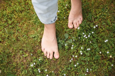 Photo of Woman walking barefoot on green grass outdoors, top view