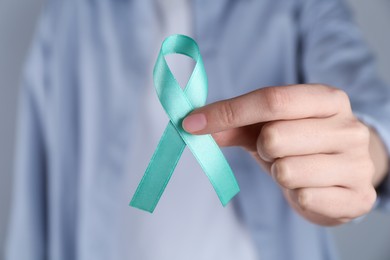 Photo of Woman holding turquoise awareness ribbon, closeup view