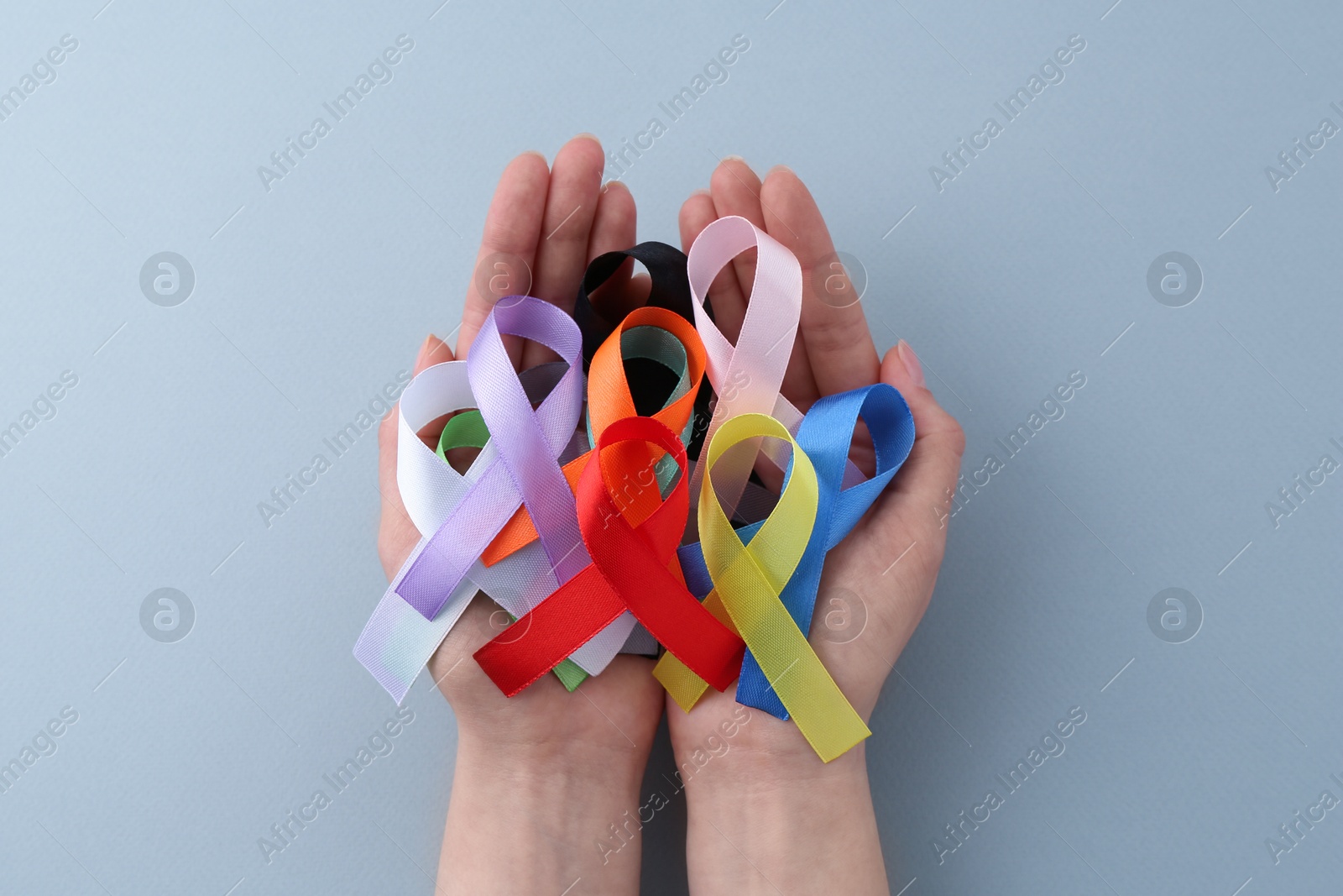 Photo of Woman with many colorful awareness ribbons on grey background, top view