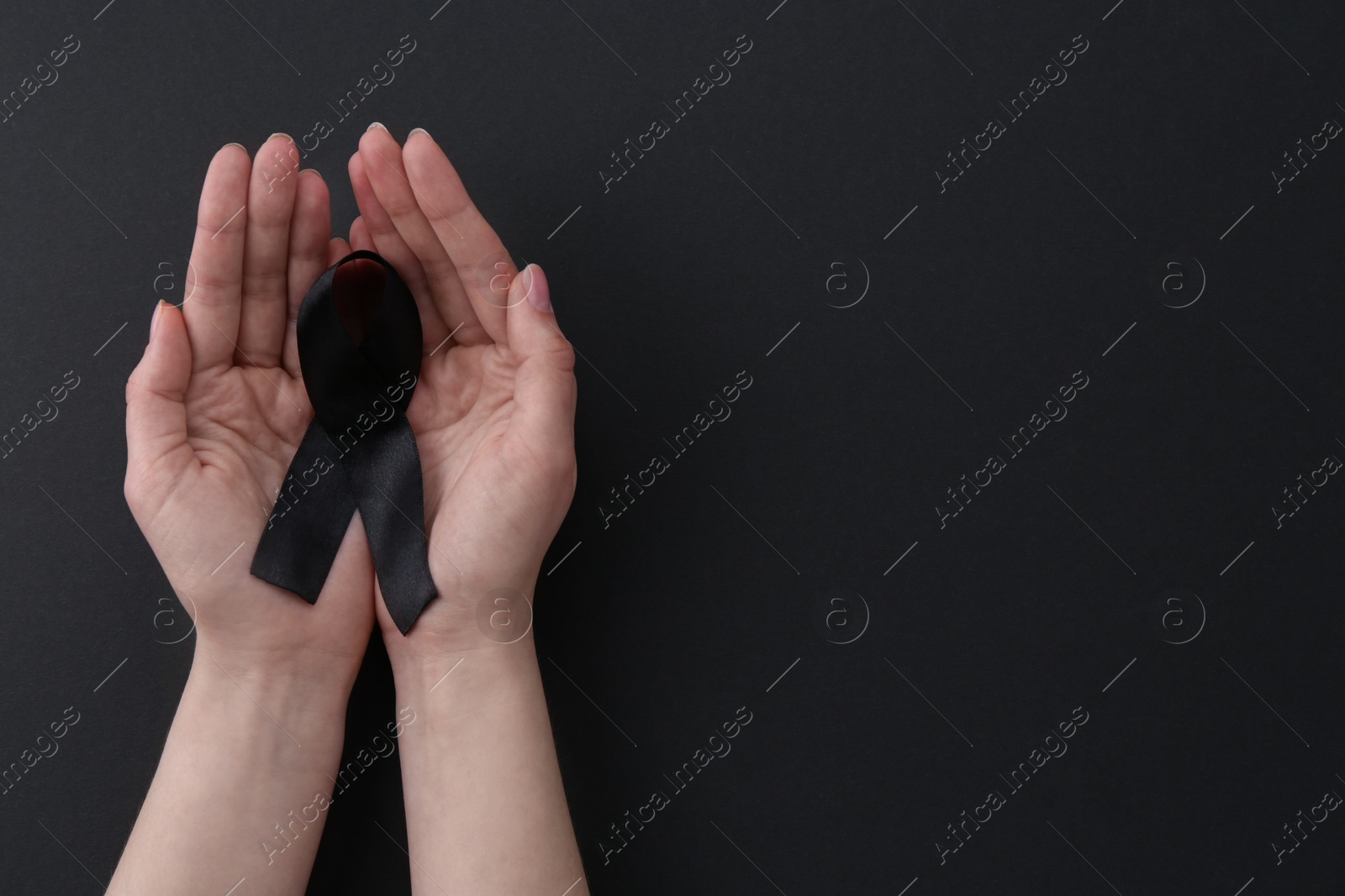 Photo of Woman with black awareness ribbon on color background, top view. Space for text