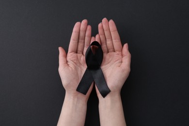 Photo of Woman with black awareness ribbon on color background, top view