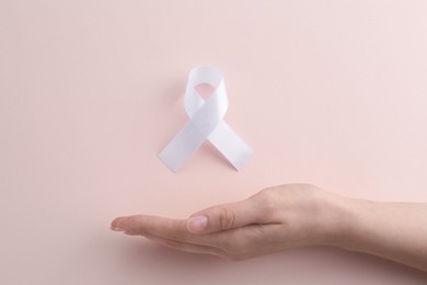 Photo of Woman with white awareness ribbon on beige background, top view