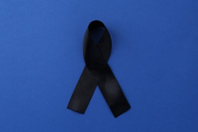 Black awareness ribbon on blue background, top view