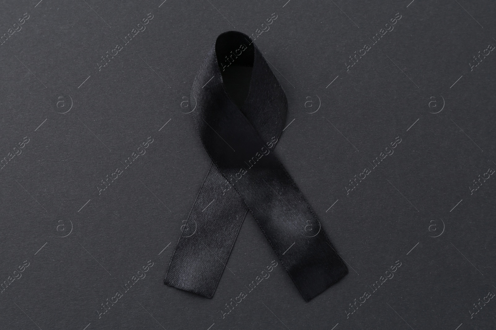 Photo of Black awareness ribbon on color background, top view