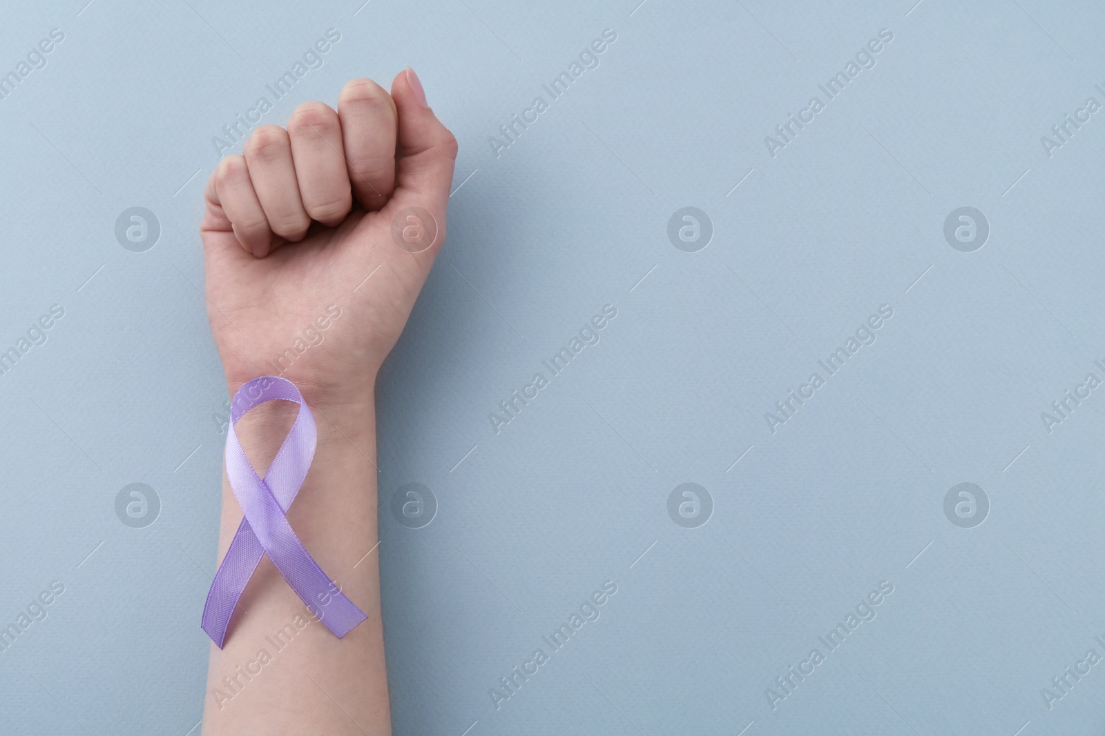 Photo of Woman with violet awareness ribbon on light blue background, top view. Space for text