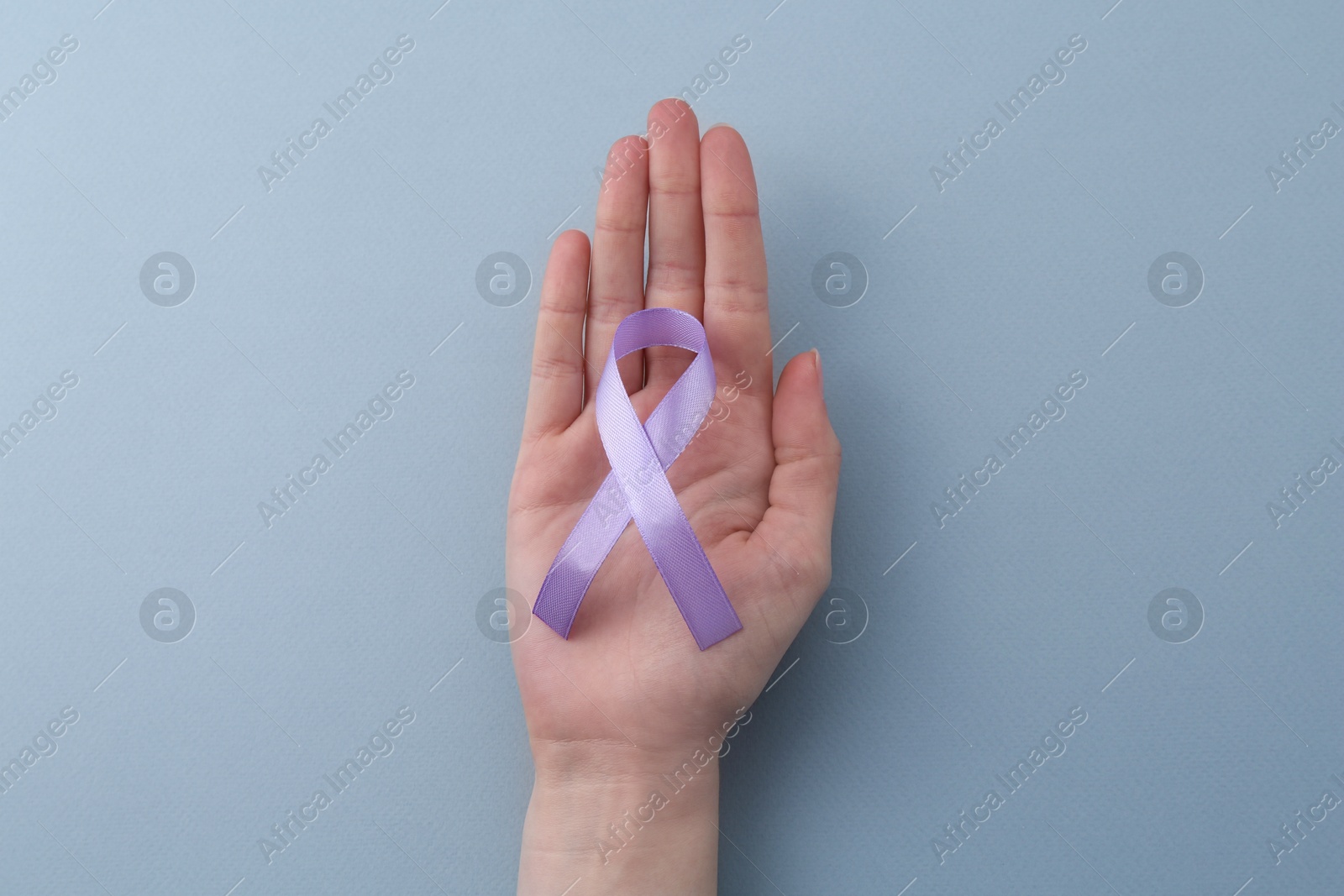 Photo of Woman with violet awareness ribbon on light blue background, top view