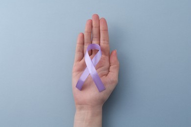 Photo of Woman with violet awareness ribbon on light blue background, top view