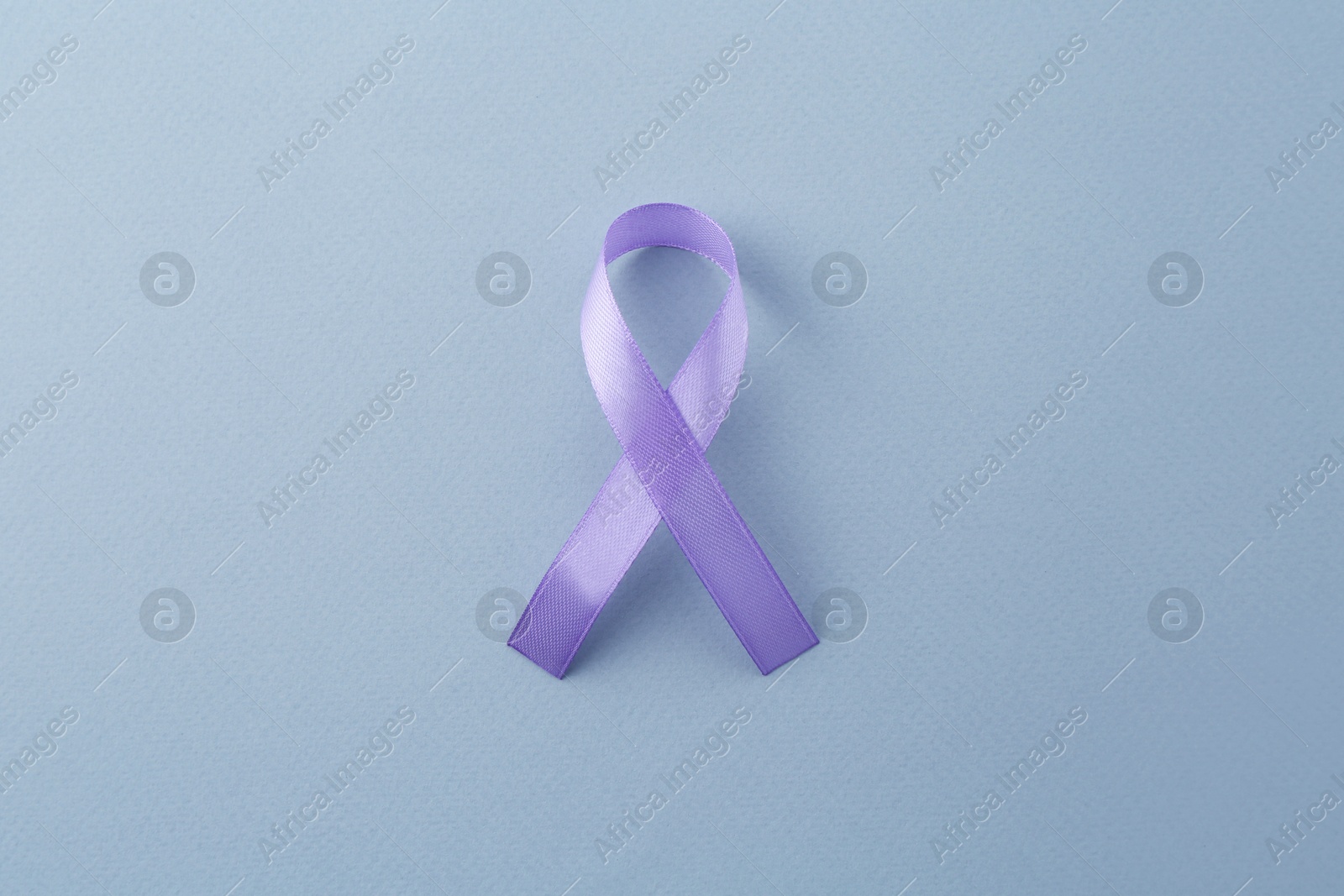 Photo of Violet awareness ribbon on light blue background, top view