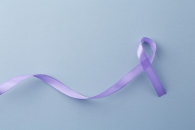 Photo of Violet awareness ribbon on light blue background, top view