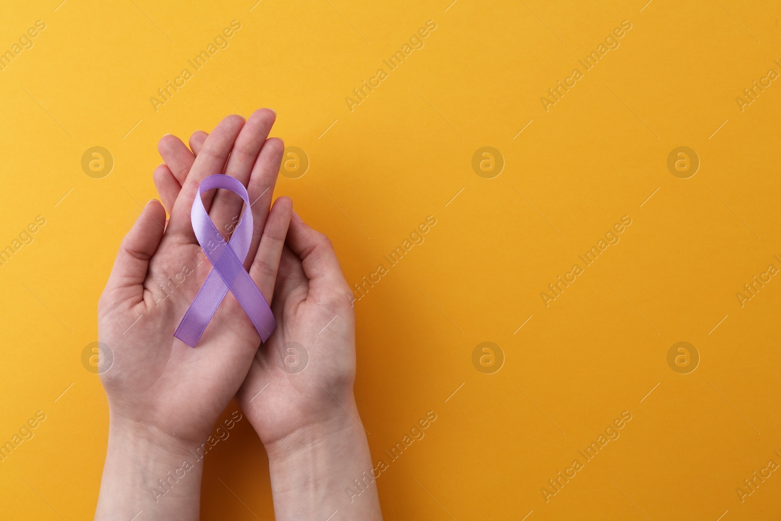 Photo of Woman with violet awareness ribbon on orange background, top view. Space for text