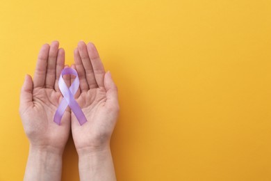 Photo of Woman with violet awareness ribbon on orange background, top view. Space for text