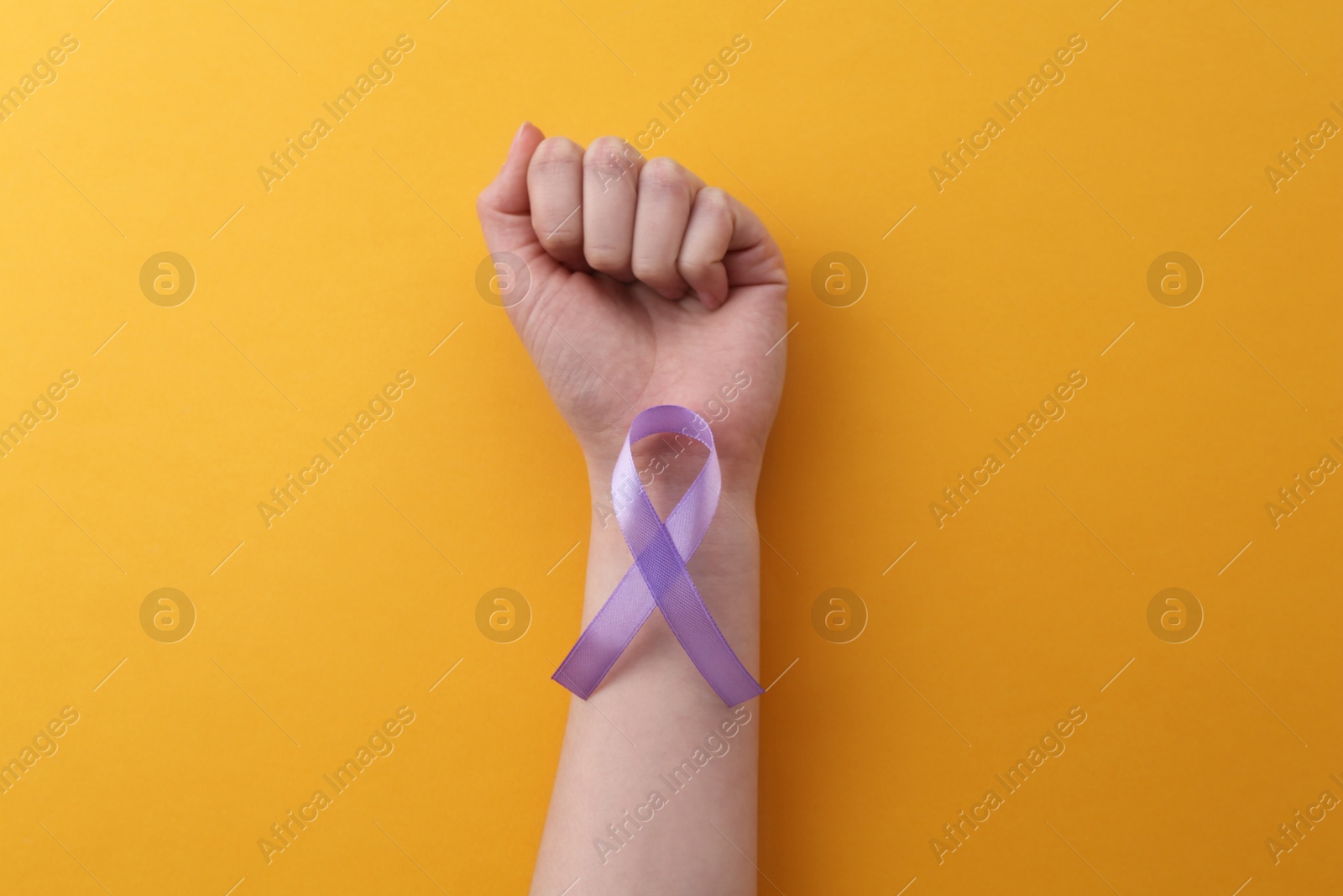 Photo of Woman with violet awareness ribbon on orange background, top view