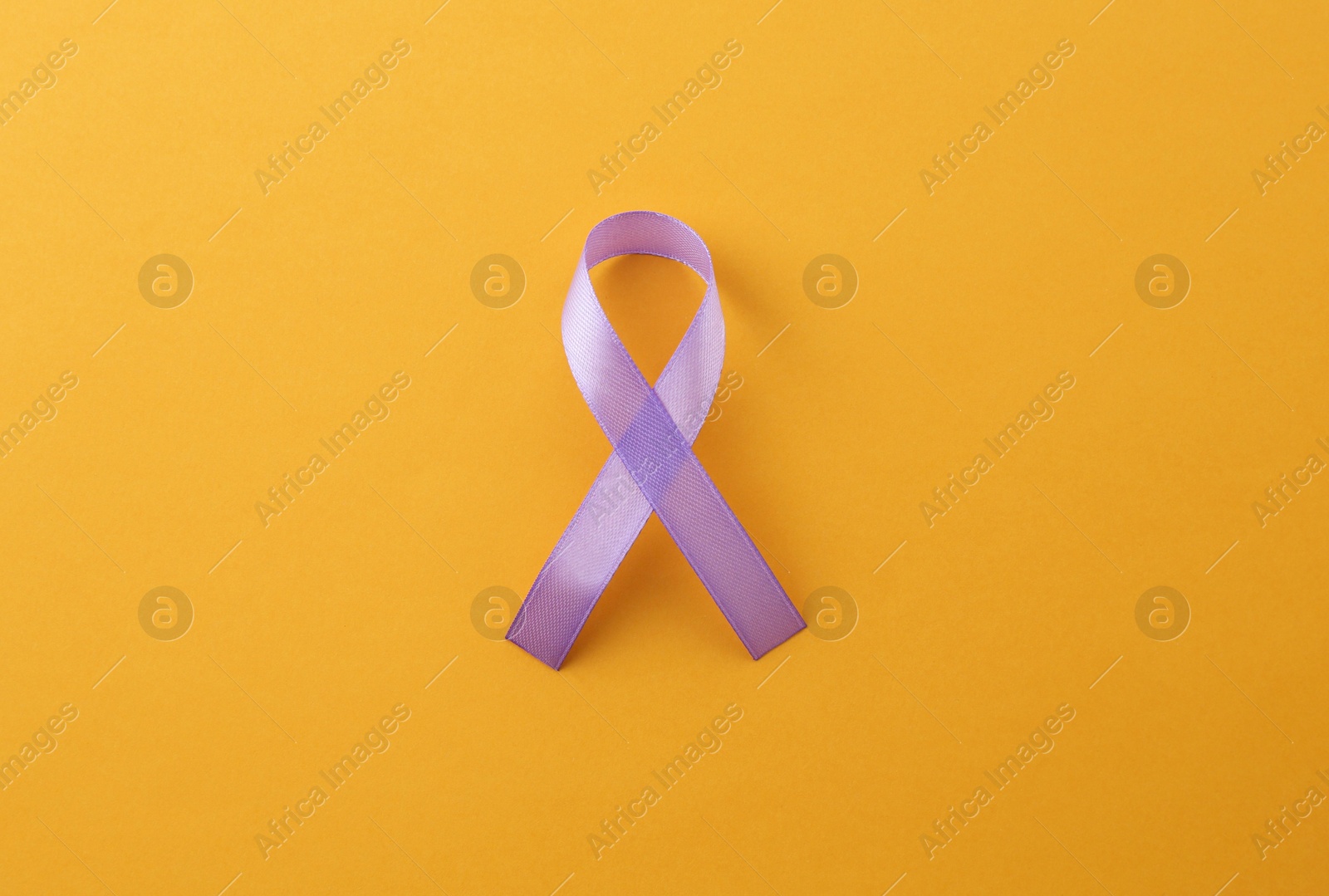 Photo of Violet awareness ribbon on orange background, top view