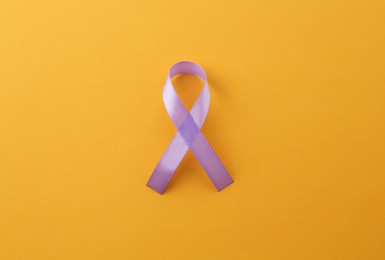 Photo of Violet awareness ribbon on orange background, top view