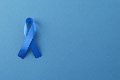 Photo of Blue awareness ribbon on color background, top view. Space for text